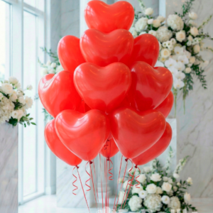 Букет красных латексных воздушных шаров в форме сердца с лентами в праздничном интерьере